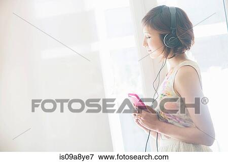 Woman listening to music on mobile phone with earphones View Large Photo Image Stock Photo - Woman listening to music on mobile phone with earphones. Fotosearch