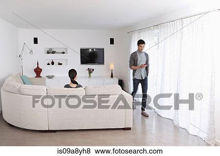 Stock Photo - Woman looking at man walking away with mobile phone. Fotosearch