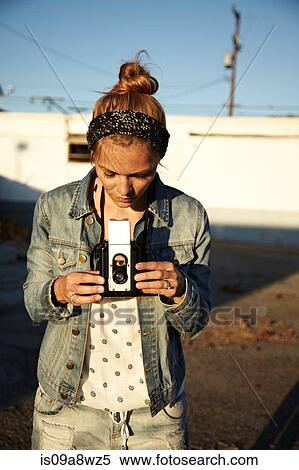 Stock Photography - Woman looking at vintage camera. Fotosearch