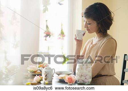 Stock Photograph - Woman looking down at tea cup. Fotosearch