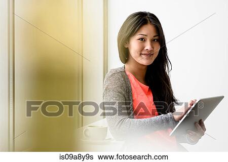 Stock Photograph - Woman looking up from digital tablet. Fotosearch