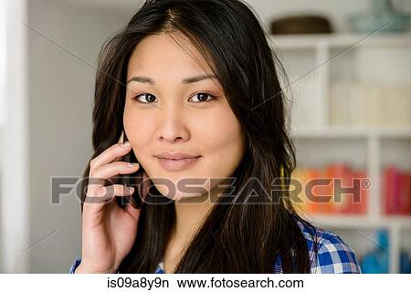 Picture - Woman on mobile phone looking at camera. Fotosearch
