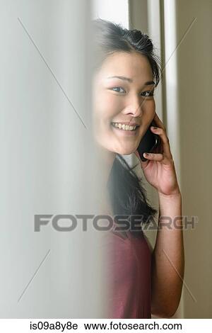 Stock Image - Woman on mobile phone looking at camera. Fotosearch