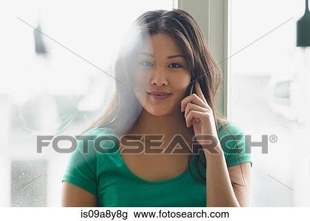 Stock Image - Woman on mobile phone looking at camera. Fotosearch