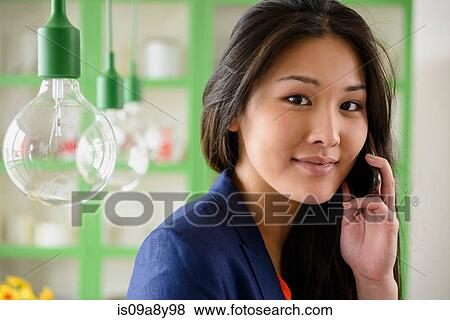 Stock Photo - Woman on mobile phone looking at camera. Fotosearch