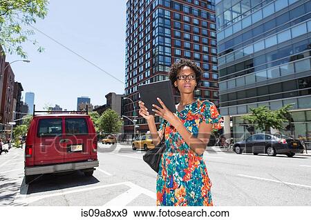 Stock Photo - Woman on street parking bay holding digital tablet. Fotosearch
