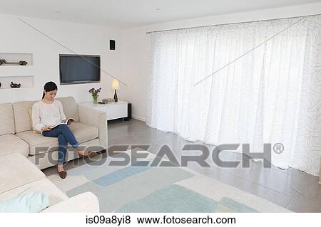 Woman reading in living room View Large Photo Image Stock Photo - Woman reading in living room. Fotosearch
