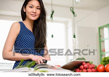 Stock Image - Woman slicing tomatoes looking at camera. Fotosearch