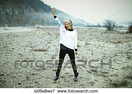 Woman standing in remote setting making peace sign View Large Photo Image Stock Photo - Woman standing in remote setting making peace sign. Fotosearch
