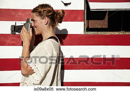 Stock Photography - Woman taking photograph using vintage camera. Fotosearch