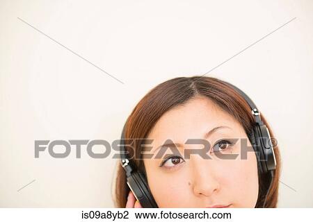 Stock Image - Woman wearing earphones looking upward. Fotosearch