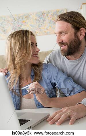 Stock Image - Woman with credit card looking at husband. Fotosearch