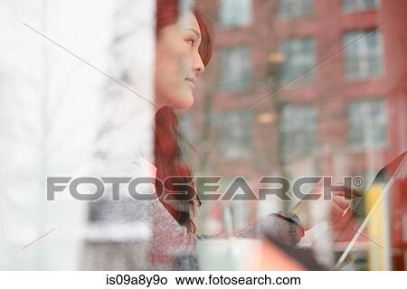 Woman with digital tablet looking out of glass window View Large Photo Image Picture - Woman with digital tablet looking out of glass window. Fotosearch
