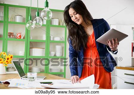 Woman with digital tablet looking through paperwork View Large Photo Image Stock Photography - Woman with digital tablet looking through paperwork. Fotosearch