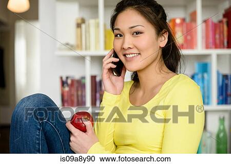 Woman with red apple listening to mobile phone View Large Photo Image Stock Image - Woman with red apple listening to mobile phone. Fotosearch