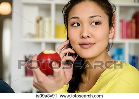 Woman with red apple listening to mobile phone View Large Photo Image Stock Image - Woman with red apple listening to mobile phone. Fotosearch