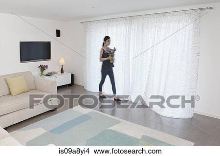 Woman with vase of flowers walking past curtains View Large Photo Image Picture - Woman with vase of flowers walking past curtains. Fotosearch
