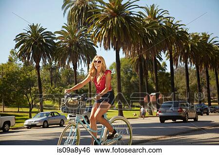 Women cycling on the street side View Large Photo Image Stock Photograph - Women cycling on the street side. Fotosearch
