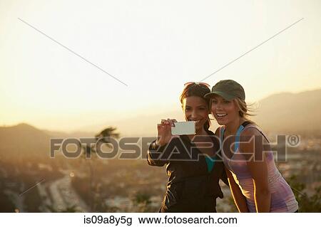 Stock Image - Women self-photographing against scenery. Fotosearch
