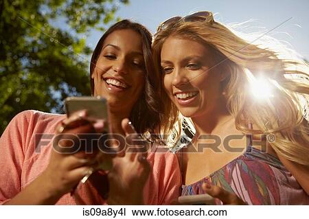 Stock Image - Women sharing text messages on phone. Fotosearch