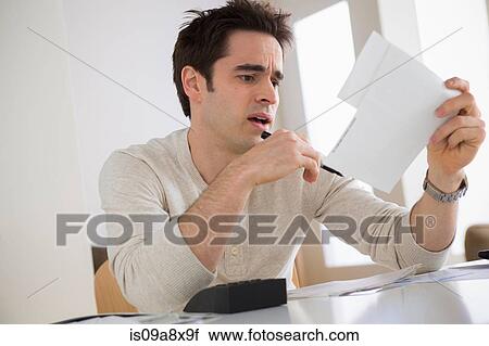 Stock Image - Worried looking man wearing holding document. Fotosearch