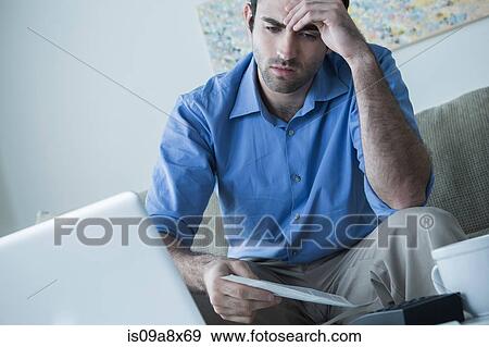 Stock Photo - Worried man with hand on head holding bills. Fotosearch