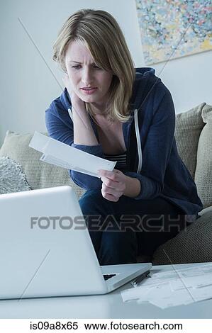 Stock Photography - Worried young woman holding bills. Fotosearch