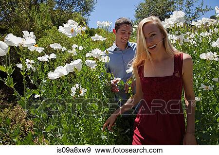 Young couple in field with white flowers View Large Photo Image Stock Photo - Young couple in field with white flowers. Fotosearch