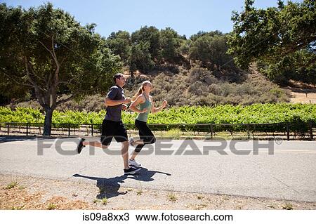 Stock Image - Young couple jogging on road. Fotosearch