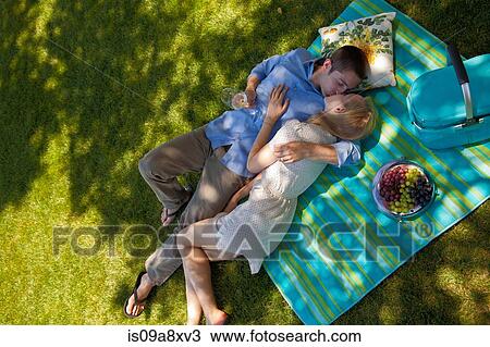 Stock Image - Young couple kissing on picnic blanket, overhead view. Fotosearch