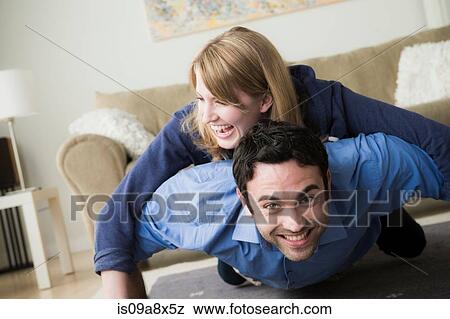 Stock Photo - Young couple lying on floor, woman on top of man. Fotosearch