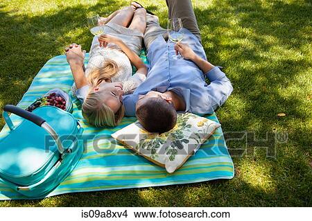 Picture - Young couple lying on picnic blanket. Fotosearch