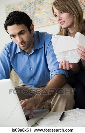 Stock Image - Young couple paying bills online. Fotosearch