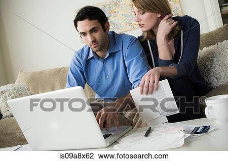 Stock Image - Young couple paying bills online. Fotosearch