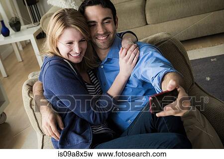 Stock Photo - Young couple photographing themselves on cell phone. Fotosearch