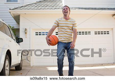 Stock Photography - Young man holding basketball laughing, portrait. Fotosearch