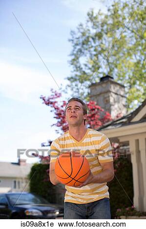 Stock Image - Young man holding basketball. Fotosearch