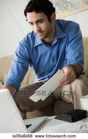 Stock Photo - Young man paying bills online. Fotosearch
