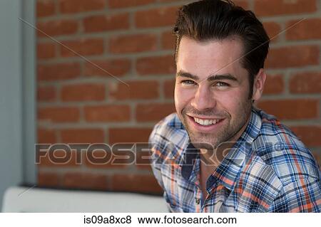 Stock Photo - Young man wearing checked shirt, smiling. Fotosearch