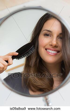 Young woman brushing hair in mirror View Large Photo Image Stock Photo - Young woman brushing hair in mirror. Fotosearch