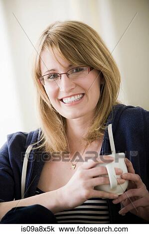 Stock Image - Young woman holding coffee. Fotosearch