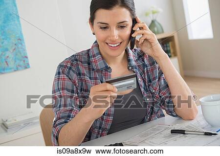 Stock Photo - Young woman on cell phone with credit card. Fotosearch