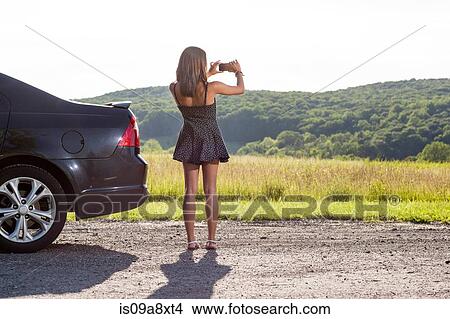 Young woman photographing rural scene with camera phone View Large Photo Image Picture - Young woman photographing rural scene with camera phone. Fotosearch