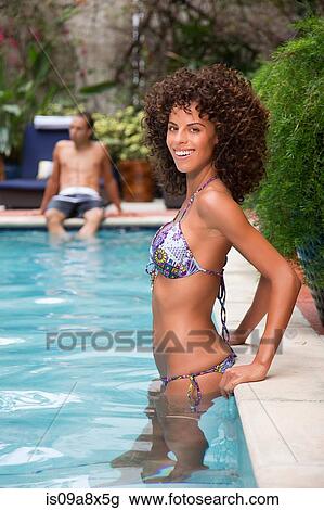 Stock Image - Young woman wearing bikini in swimming pool. Fotosearch