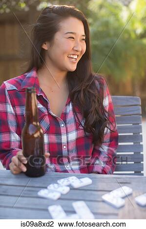 Stock Image - Young woman with bottle of beer. Fotosearch