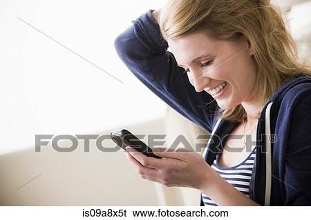 Stock Photograph - Young woman with cell phone and hand in hair. Fotosearch