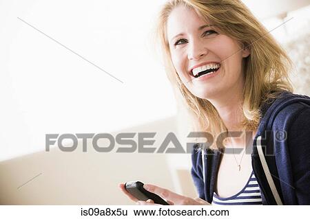 Stock Photograph - Young woman with cell phone, laughing. Fotosearch