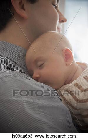Stock Image - Baby boy sleeping on father's shoulder, close up. Fotosearch