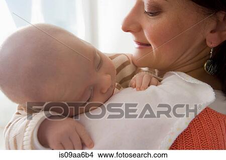 Baby boy sleeping on mother's shoulder, close up View Large Photo Image Picture - Baby boy sleeping on mother's shoulder, close up. Fotosearch