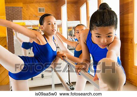 Stock Image - Ballerinas warming up at the barre in ballet school. Fotosearch
